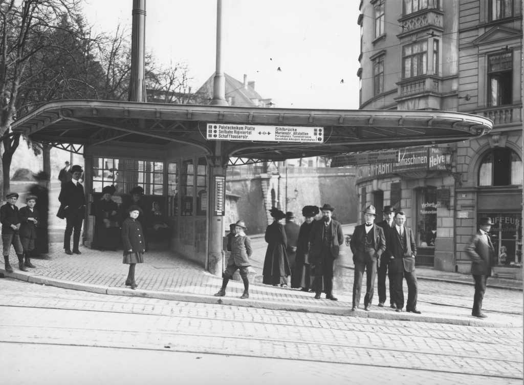 Warten auf das Tram anno 1914; hutbedeckte Häupter sind die Regel. Alte Haltestellenlage an der Verzweigung Weinbergstrasse mit eiserner Wartehalle von 1909, im Hintergrund links Hirschen-, rechts Seilergraben. (Archiv VBZ)